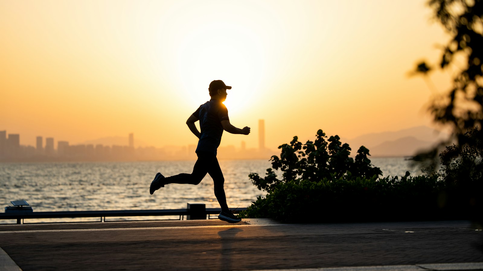 A runner on a waterfront path at sunrise